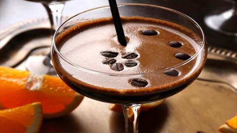 cocktail with coffee beans and straw with orange wedges